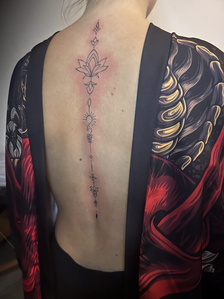 Tattoo of a flower made with thin lines on the spine
